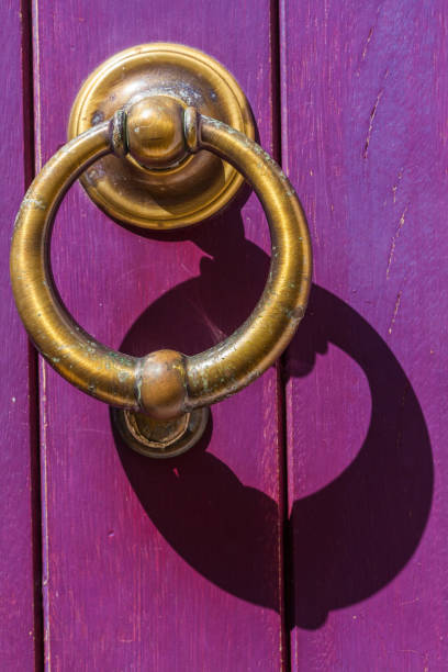 istock A weathered brass door knocker, casting a shadow on a vibrant purple door 2187627534