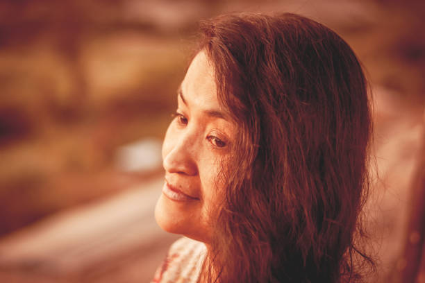 Close-up of a woman at sunset, bathed in warm tones, radiating nostalgia.