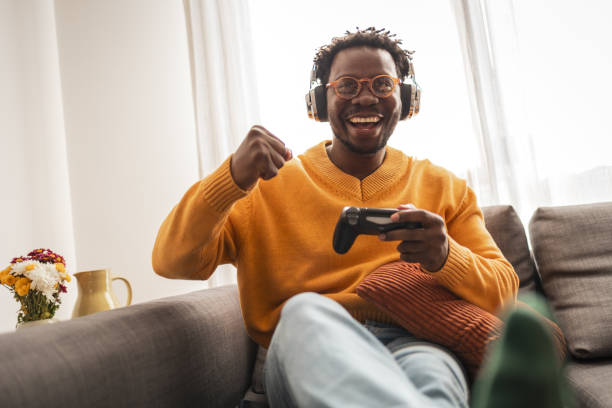 istock Joyful man gaming at home with headphones and controller 2187642501
