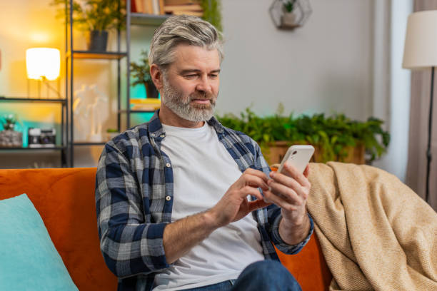 istock Happy middle-aged senior man using smartphone getting message reading good social media news at home 2187642867