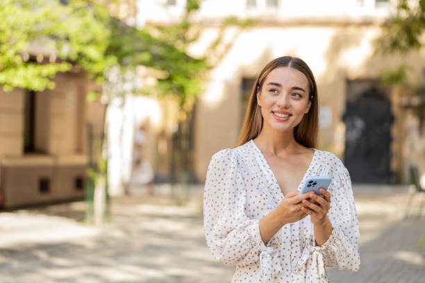 istock Caucasian young woman using smartphone typing texting social media messages e-mail in city street 2187643874