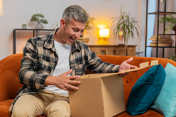 istock Happy customer man unpacking delivery parcel opening cardboard box receiving purchase gift at home 2187643910