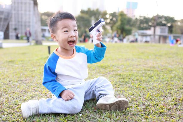 small boy taking a picture using retro film camera on green grass and fallen leaves background