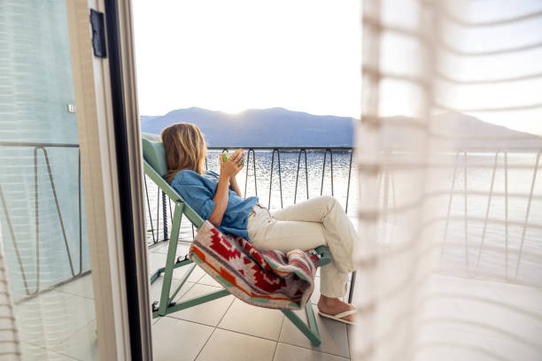 istock Woman Relaxing on Balcony with Coffee at Lakeside Sunset 2187650251
