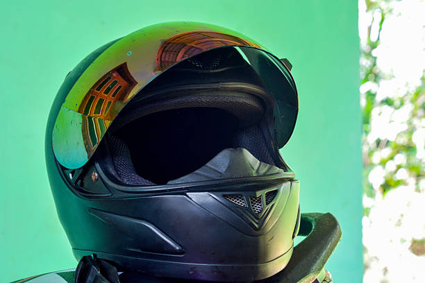 Man holding a motorcycle helmet with a motorbike parked in the background. Symbol of road safety, biker lifestyle, and responsible riding in an urban or residential neighborhood setting.