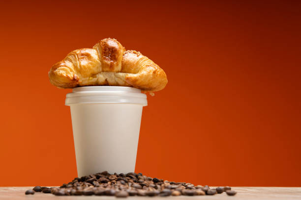 studio photo of croissant, bean and coffee cup delivery on warm background
