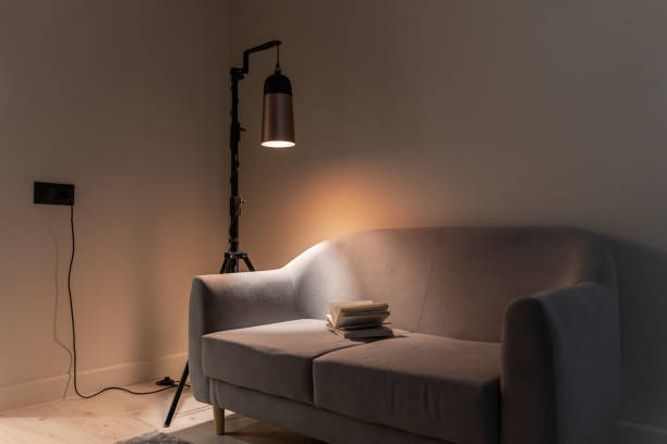 istock soft sofa in living room, book and floor lamp. soft lighting. illuminated by lamp. space for relaxation and moments of calm. 2187663449