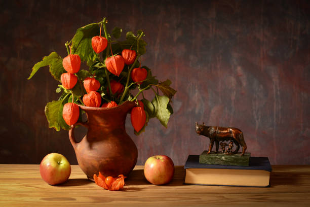 Still life, Alkekengi in a ceramic vase, apples, a book and a figure on the table