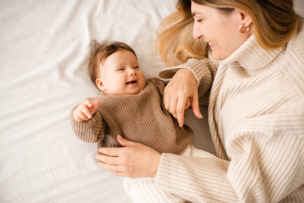 istock Baby girl lying in bed with mom 2187667794