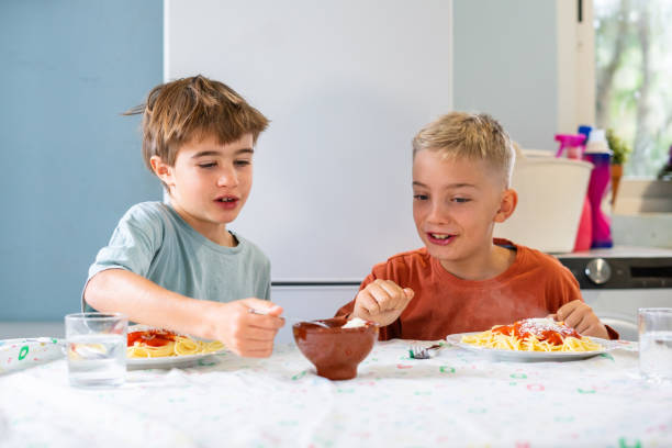 istock Two Caucasian children eating pasta at home 2187670086