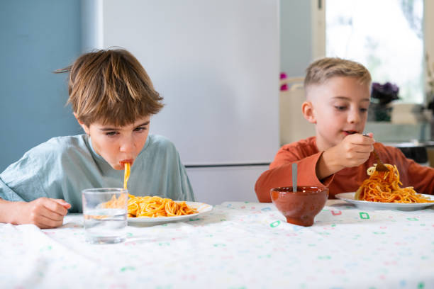 istock Children eating spaghetti in the kitchen at home 2187670091