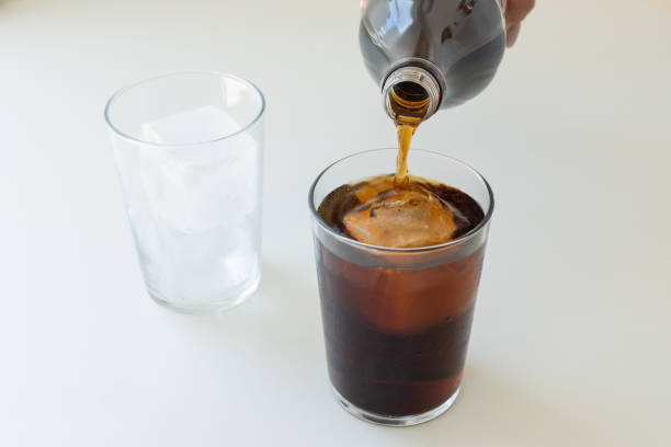 pouring a bottle of cola into glasses, on a white background