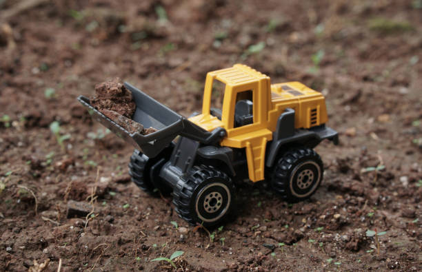 istock Yellow wheel loader or tractor toy on soil or ground background. construction image concept with heavy equipment. 2187677215