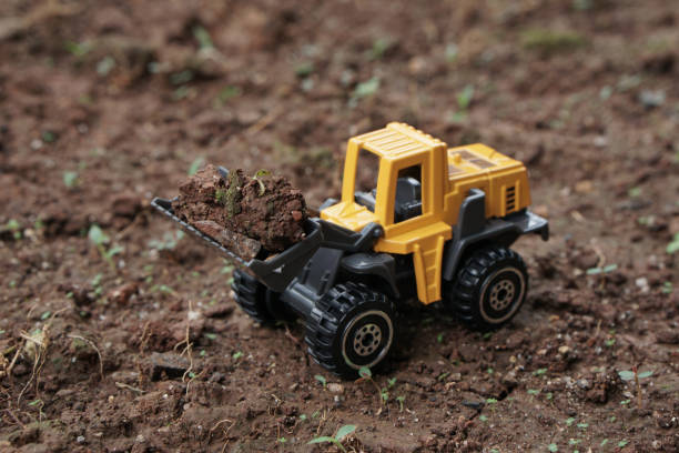 istock High angle view of Yellow wheel loader or tractor toy on soil or ground background. construction image concept with heavy equipment. 2187677218