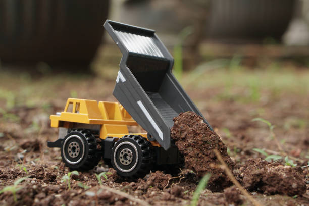 istock yellow small dump truck toy model dumping soil on the ground. Rear view. construction or mining industry concept image. 2187677268