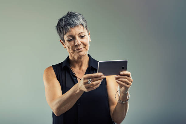 istock Mature adult woman using smartphone in studio setting 2187680392