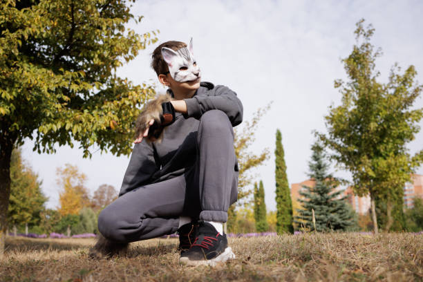 istock Quadrober boy in mask sits on grass in city park 2187680846