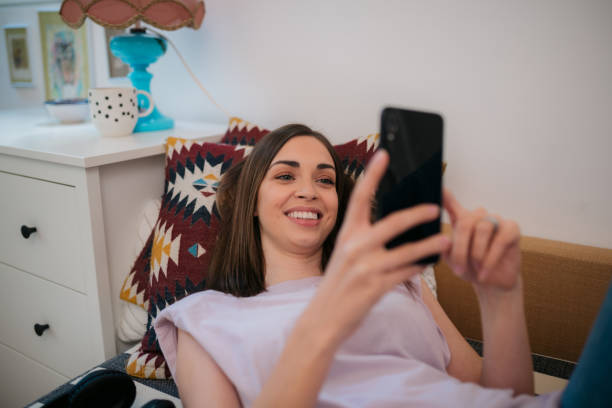 istock Smiling woman relaxing on sofa using smart phone at home 2187681141