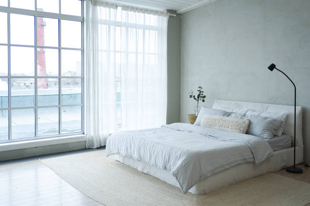 istock Stylish loft bedroom interior. Spacious design apartment with light walls large windows big bed. Clean modern decoration with elegant furniture in minimalist Scandinavian style 2187684389