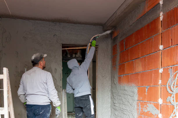 istock Plasterer throws plaster on the walls in a new house.  A worker hand removes excess plaster with leveler 2187686444