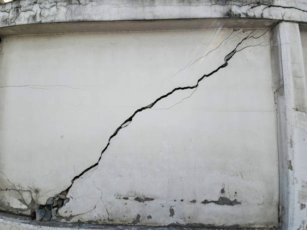 Large cracked concrete wall, a broken exterior barrier resulting from an earthquake's impact.