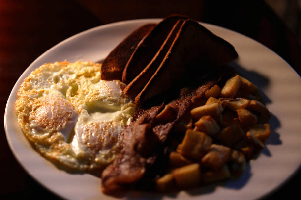 Egg, Bacon, Home Fries, and Toasted White Bread on a white plate: Traditional American Breakfast
