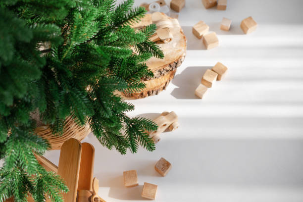 istock Wooden toys in rustic style, fir tree branches and cuts on white background in sunlight. Christmas minimalism decor. 2187698811