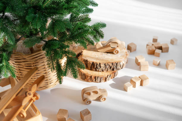 Wooden toys in rustic style, fir tree branches and cuts on white background in sunlight. Christmas minimalism decor.