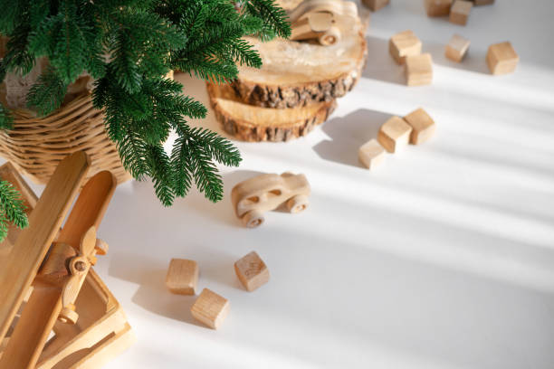istock Wooden toys in rustic style, fir tree branches and cuts on white background in sunlight. Christmas minimalism decor. 2187698843