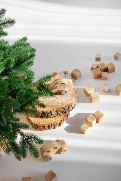 istock Wooden toys in rustic style, fir tree branches and cuts on white background in sunlight. Christmas minimalism decor. 2187698844