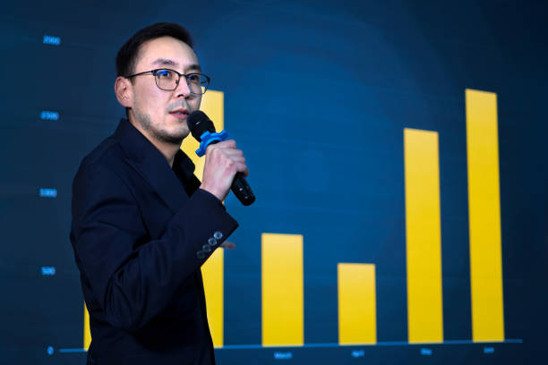 istock Speaker presenting sales growth graphic using microphone at business conference 2187698966
