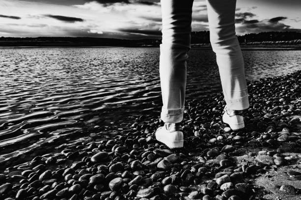 Cabo de Gata, Almeria - Spain - 01-23-2024: A pair of sneakers left on a sandy beach as gentle waves caress the shore