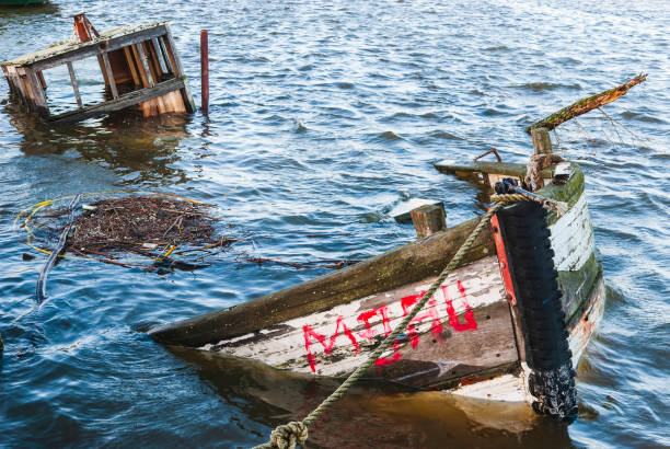 A sunken ship wreck rests at the bottom of a peaceful harbor, its hull shimmering in the sunlit sea.