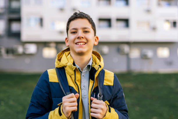 istock A young boy walking down a city street wearing a winter jacket and carrying a backpack on his shoulders 2187708352