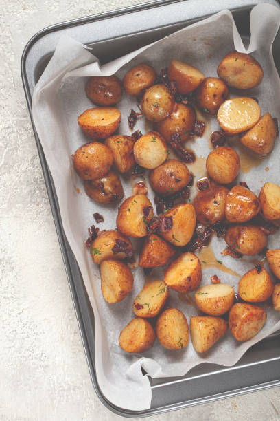istock Crispy roasted potatoes seasoned with herbs served in a baking tray on a light countertop 2187709348
