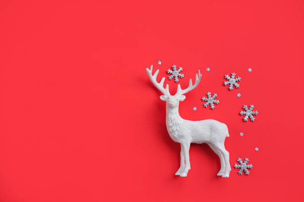 istock Decorative white reindeer figure on red background with glittery snowflakes with space for text. 2187713680