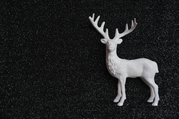 istock Decorative white deer figure on glossy black background with space for text. 2187713686