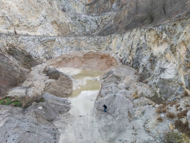 Undercover cop with gun in his hand sneaking outdoor in a quarry mine