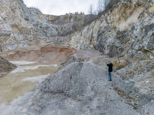 Undercover cop with gun in his hand sneaking outdoor in a quarry mine