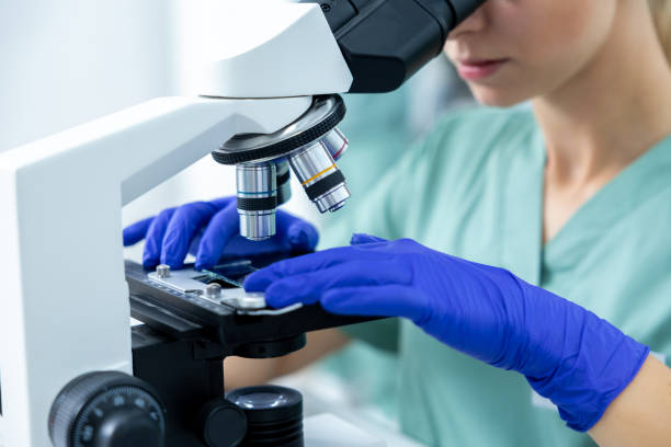 istock Medical woman in laboratory studying samples under microscope with protective gloves 2187715249