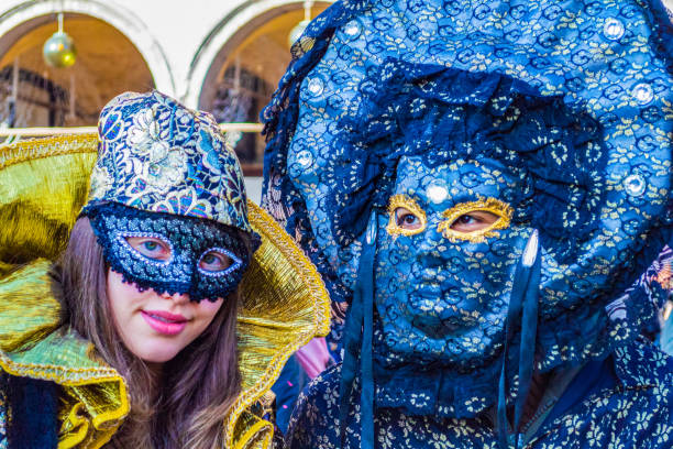 1st of March. 2025 Venice - Italy\nGorgeously dressed couple with venetian masks during the Venetian Carnival. Striking a pose near the Doge Palace in Venice Italy