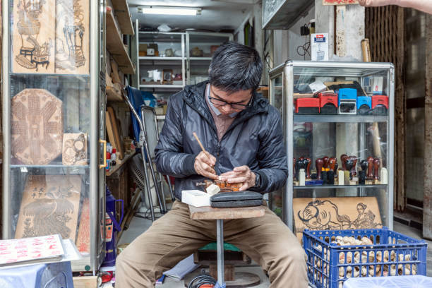 Hanoi, Vietnam - March 20, 2024: Vietnamese man making stamps on the Weekend Walking Street in Hanoi