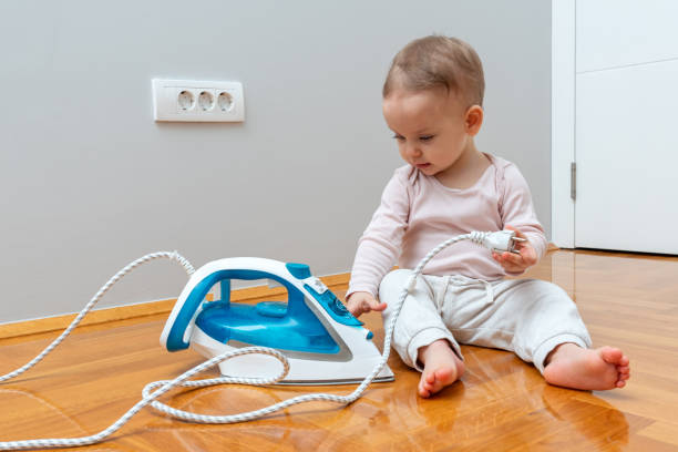 Toddler innocently playing with an iron plug, unaware of potential danger