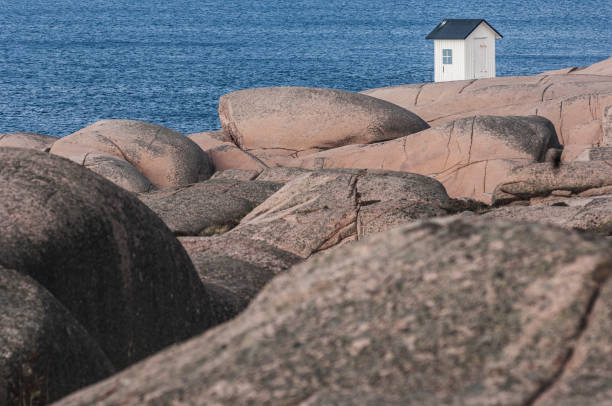 istock Rocky shoreline with a small white structure under a clear sky at the edge of a vast blue ocean 2187719899