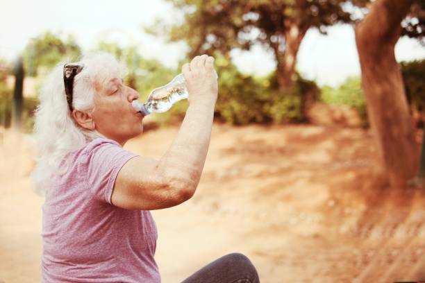 istock Thirst in the desert. An elderly lady greedily drinks water from a bottle. 2187721833