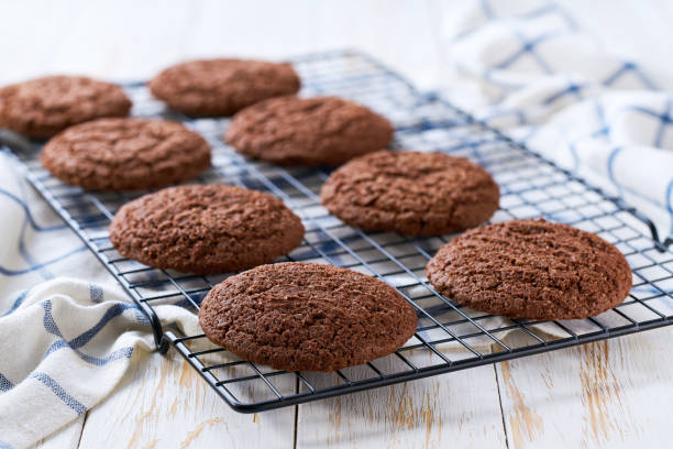 istock Freshly baked American chocolate cookies cooling on a black wire rack, with in a light kitchen table, selective focus. 2187722790