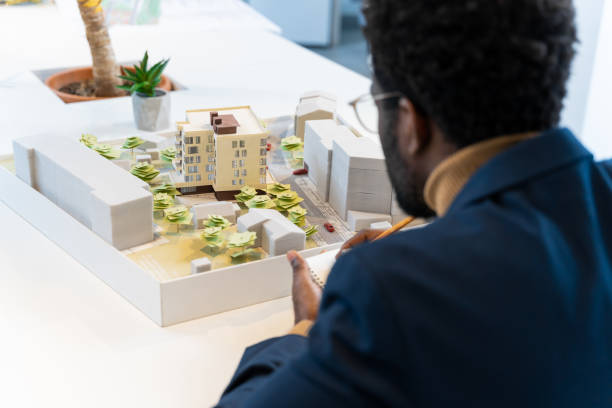 istock African american young architect sitting at the table and analyzing new model 2187723276