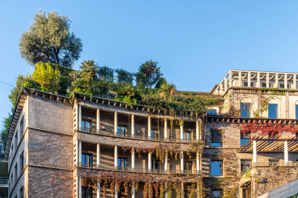 istock Urban building with lush rooftop garden, featuring trees and greenery cascading over the structure, blending architecture with nature under clear blue sky, Milan, Italy. Eco friendly urban environment 2187727190