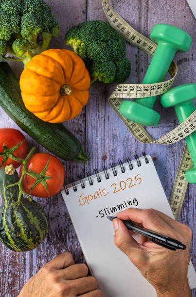 istock Slimming, two hands writing New Year's resolutions on a notepad, self-improvement concept. 2187727257