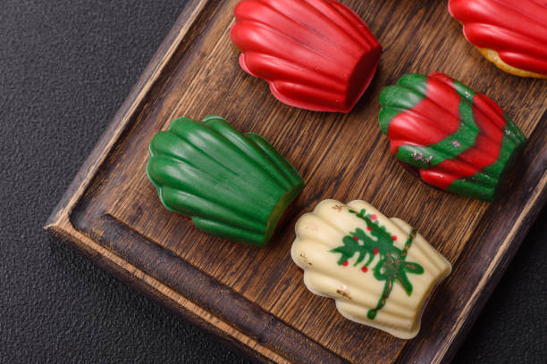 Close-up view of colorful red, green and white peppermint candies served in a ceramic bowl, creating a festive holiday atmosphere with rich textures and vibrant colors.